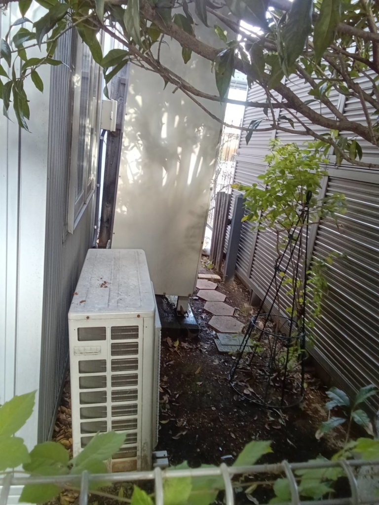 交換前のエコキュート。住宅脇に設置された貯湯タンクとヒートポンプユニット。